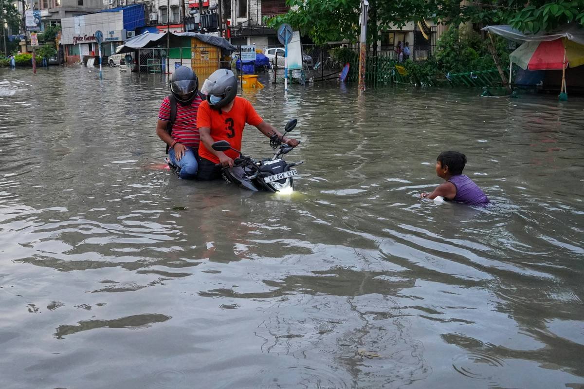 A flooded street showing someone carrying their dog to safety.