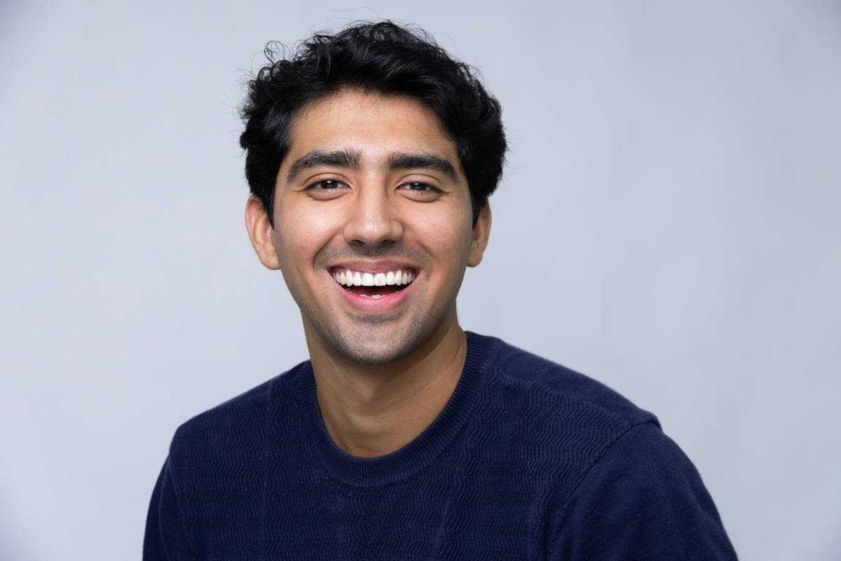 A smiling young man in a dark blue sweater