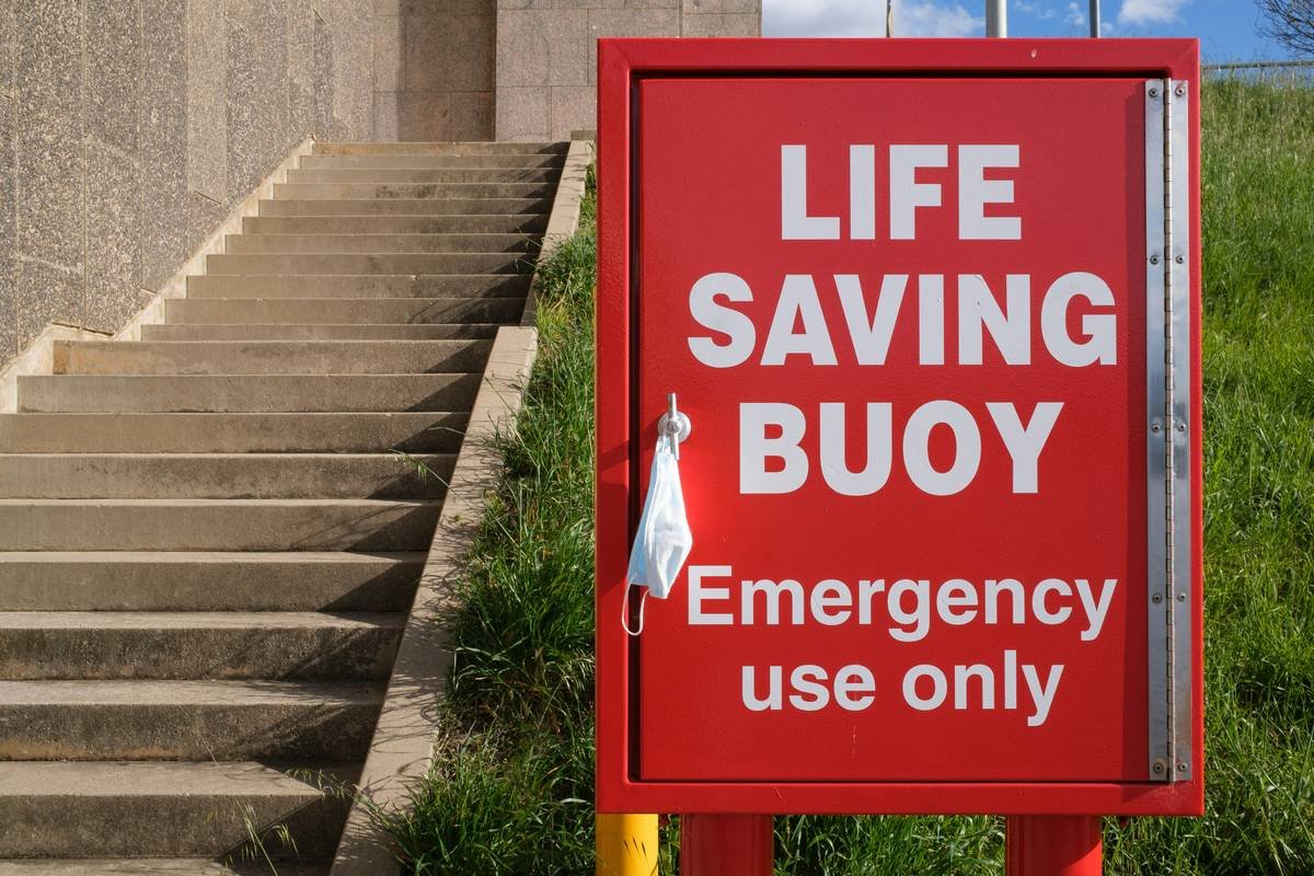 Red life saving buoy cabinet with face mask on the handle and stairs leading up.