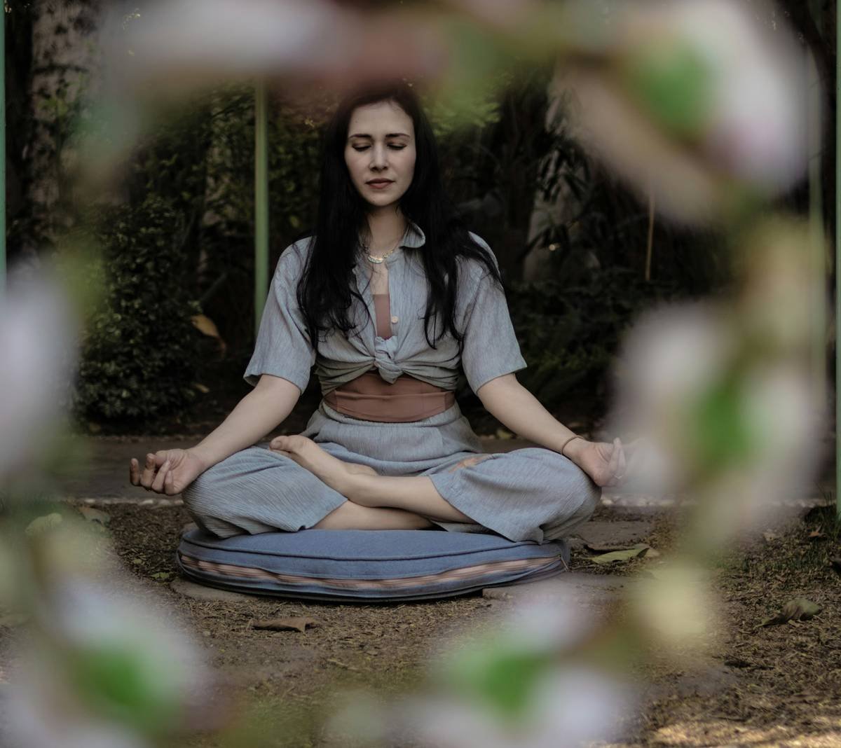 Young Egyptian woman sitting in a Yoga pose surrounded by a floral wreath in the foreground